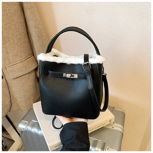 Close-up of black lychee leather bucket bag with white faux fur trim and silver turn-lock