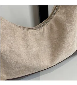 Detailed close-up of soft beige suede fabric and brown piping on the stylish crossbody bag