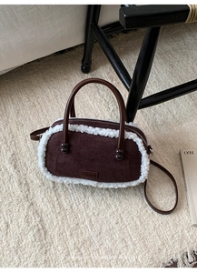 Détail d'un sac bowling en daim marron avec bordure en polaire blanche et poignées