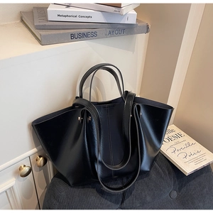 Grand sac fourre-tout noir vintage sur texture velours dans un décor de chambre chic
