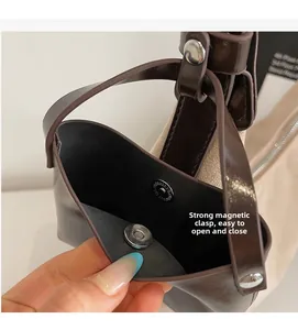Close-up of the circular magnetic snap closure and leather interior of the brown tote bag