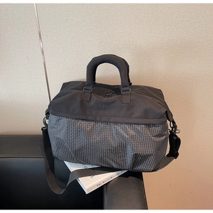 Detail of a large capacity travel tote bag featuring grey plaid and black fabric textures
