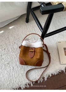 Détail du sac seau en daim marron avec garniture en fausse fourrure et boucle dorée