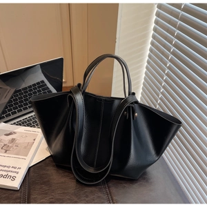 Détail d'un grand sac cabas noir en similicuir avec ordinateur dans un décor de bureau