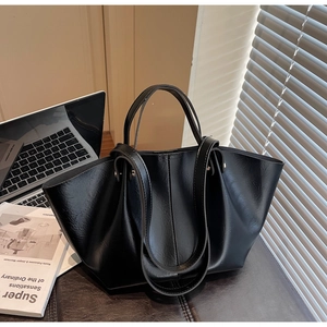 Détail d'un grand sac cabas noir brillant avec une structure plissée posé sur un bureau