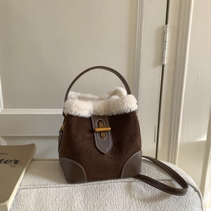 Detailed macro view of deep brown bucket bag with soft faux fur trim and golden metal lock
