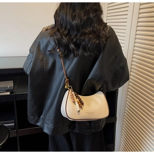 Sac sous le bras crème avec bordure marron et perles de bois porté par un modèle