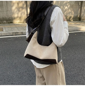 Street style view of a beige suede hobo bag with dark brown leather details