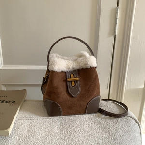 Close-up of vintage brown suede bucket bag with white faux fur trim and gold twist lock