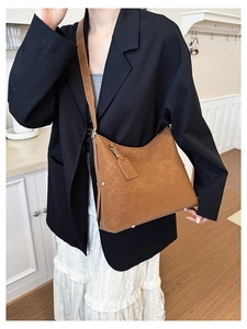 Deep caramel leather hobo bag styled with a black blazer in a warm kitchen setting