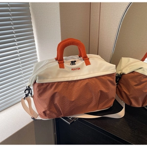 Detail of a large color-block travel tote bag with top handles and adjustable shoulder strap