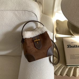 Detail of vintage brown suede bucket bag featuring plush white faux fur trim and gold clasp