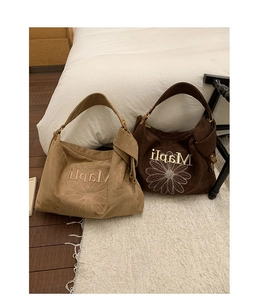 Detailed embroidery of daisy flower on suede hobo tote bag with adjustable strap