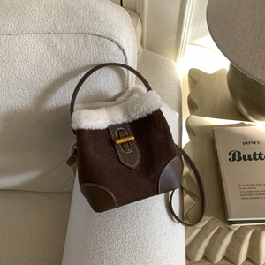 Detail of vintage brown suede bucket bag with white faux fur trim and gold metal lock