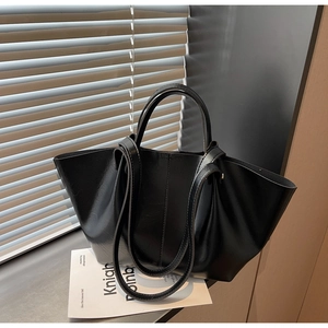 Sac fourre-tout en cuir noir poli avec deux poignées dans un décor de fenêtre épuré