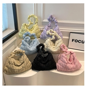 Macro shot of stylish quilted cloud bags in seven vibrant colors on modern display steps