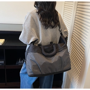 Detail of grey checkered large capacity tote bag with black strap in lifestyle setting
