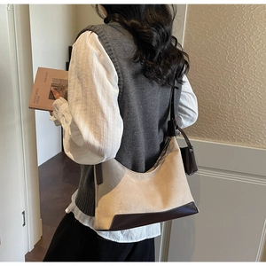 Detail of retro suede dumpling bag with brown leather trim and curved crescent silhouette