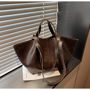 Gros plan sur un sac cabas vintage en similicuir marron foncé avec texture brillante