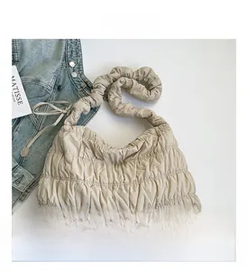 Detail of beige quilted nylon cloud bag with soft pleated texture and wide strap