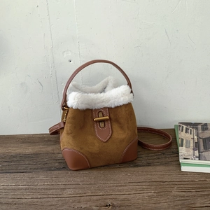 Detail of brown frosted bucket bag with white faux fur trim and gold metal clasp closure