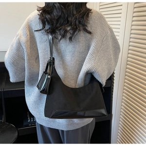 Detail of black tote bag with matching small pouch and leather shoulder strap on model