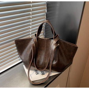 Gros plan d'un sac cabas vintage marron foncé avec texture huilée et détails de bandoulière
