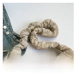 Detail of soft padded shoulder strap on a beige pleated nylon crossbody bag