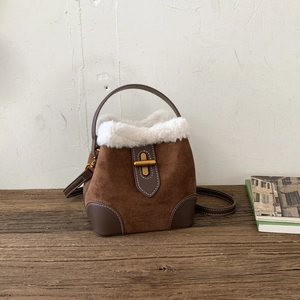 Close-up of vintage brown suede bucket bag with white faux fur trim and gold metal clasp