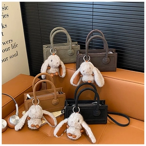 Detail view of four vintage-style matte velvet handbags with cute plush bunny charms
