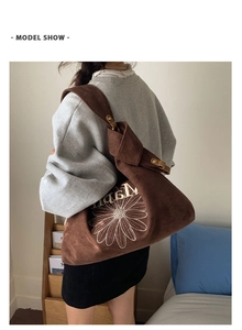 Close-up of brown suede tote bag featuring white daisy embroidery and adjustable strap