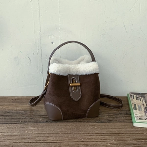 Detail view of the vintage brown suede bucket bag with white faux fur trim and gold lock