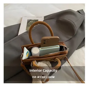 Interior view of small brown shoulder bag showing capacity for phone and cosmetics