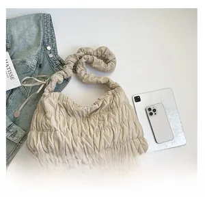 Detailed top view of a beige quilted nylon cloud bag with soft pleated shoulder strap details