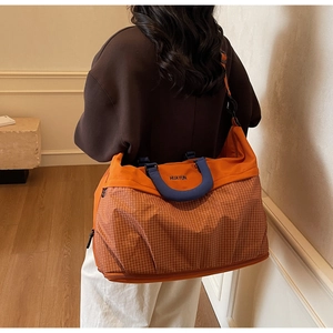 Detail of large orange travel tote with blue handles and white check pattern