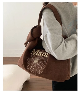 Detail of brown suede tote bag featuring a white daisy print and knotted strap detail
