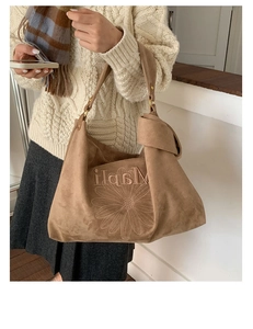 Close-up of suede tote bag with daisy embroidery and metal ring strap attachment