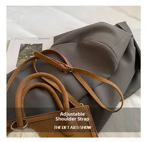 Detail of a brown leather handbag with adjustable strap and fluffy charm on a magazine