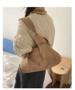 Detail of tan suede tote bag featuring daisy embroidery and wide shoulder strap
