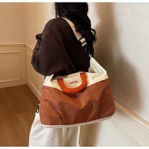 Detail of a large orange checkered travel bag with Huayun embroidery and white straps