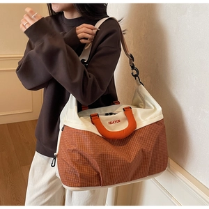 Detail view of the two-tone canvas travel bag with orange plaid pattern and sturdy handles