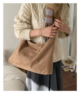 Close-up of brown suede tote bag with daisy embroidery and soft texture on model