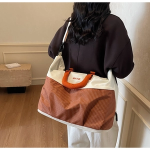 Detail of large orange checkered tote bag with adjustable shoulder strap and sturdy handles