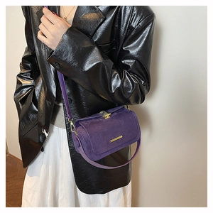 Dettaglio borsa a tracolla viola in pelle scamosciata con fibbia dorata e giacca in pelle