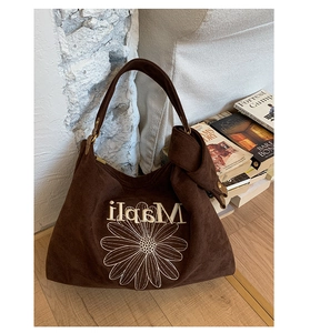 Detail of dark brown suede tote bag with daisy embroidery and metal buckle closure