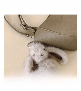 Détail d'un sac à main en cuir taupe avec un charmant pendentif lapin en peluche gris