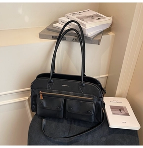 Detail of black leather tote bag with functional double front pockets and gold hardware