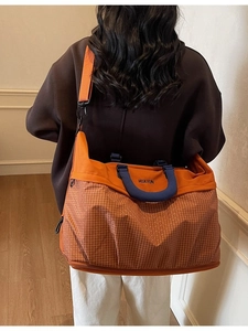 Large capacity orange and navy travel shoulder bag shown on model for short trips