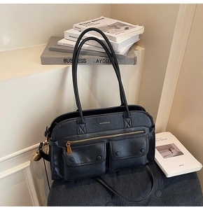 Detail view of the black tote bag with dual magnetic flap pockets and gold zipper accents