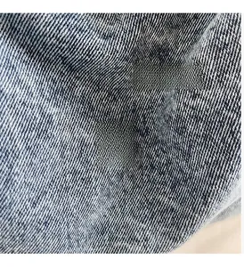 Detail of vintage blue denim bag featuring a round metallic buckle with embossed lettering